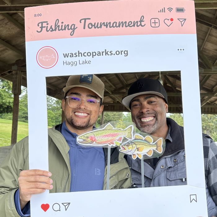 Caleb and Dishaun Berry from the Get Hooked Foundation smile while holding an Instagram selfie frame at Hagg Lake